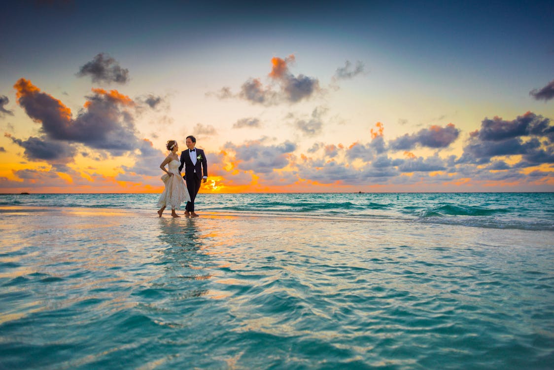 beach wedding groom attire: couple walking on beach